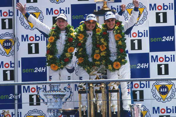 Allan McNish, Stéphane Ortelli, Laurent Aiello sul podio davanti al logo della Mobil 1 a Le Mans 1998