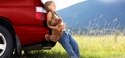 Bambino seduto sul sedile posteriore di un'auto al sole