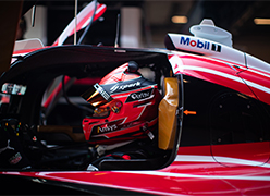A side mirror of a racing Porsche WEC car and the drivers reflection in the mirror
