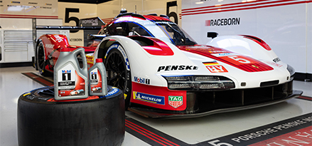 Auto da corsa Porsche nel box con flacone Mobil 1 su una gomma davanti all'auto